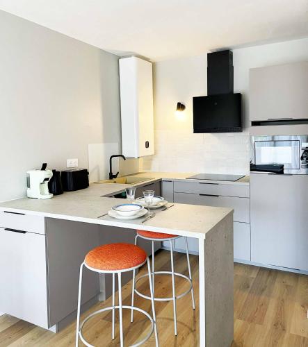 une cuisine avec deux tabourets de bar et un comptoir dans l'établissement Fenêtre sur Cour - Albi Centre - Parking Privé, à Albi