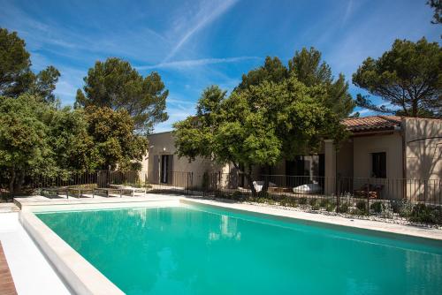 una piscina frente a una casa con árboles en La maison de Brigitte, en LʼIsle-sur-la-Sorgue