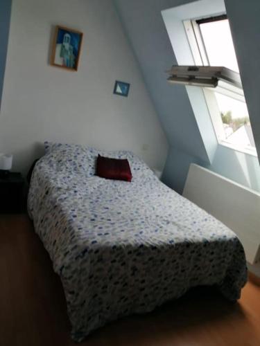 une chambre avec un lit avec un oreiller dessus dans l'établissement Maison proche de la mer, à Plestin-les-Grèves