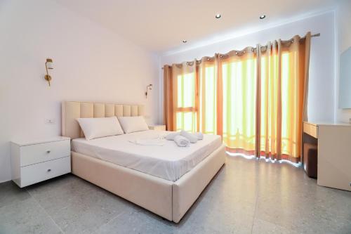 a bedroom with a white bed and a large window at Vila Dena in Vlorë