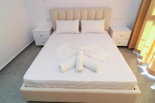 a bed with two white towels with a bow on it at Vila Dena in Vlorë