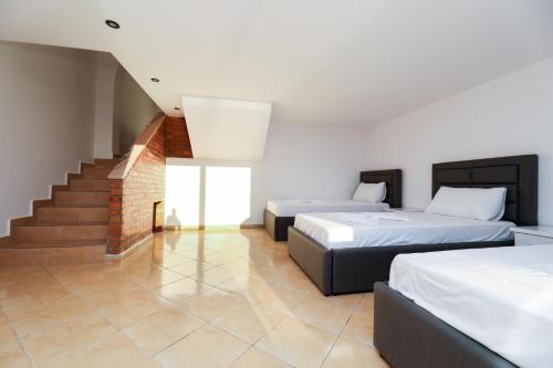 a bedroom with two beds and a staircase at Vila Dena in Vlorë