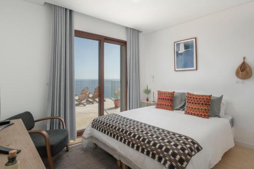 a bedroom with a bed and a balcony with the ocean at Islander - Funchal Seaside Villas in Funchal