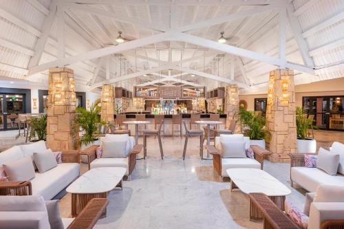 a lobby with white couches and tables and a bar at Royalton CHIC Antigua, An Autograph Collection All-Inclusive Resort - Adults Only in Saint Johnʼs