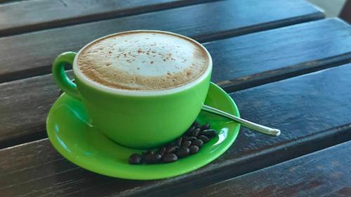 a green cup of coffee on a green plate with coffee beans at Come and go seaside B&B in Fengbin