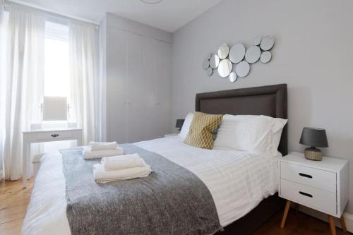 a white bedroom with a large bed with towels on it at Cosy and Chic, Quiet Apartment in Leith in Edinburgh