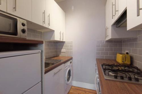a kitchen with a stove top oven next to a microwave at Cosy and Chic, Quiet Apartment in Leith in Edinburgh