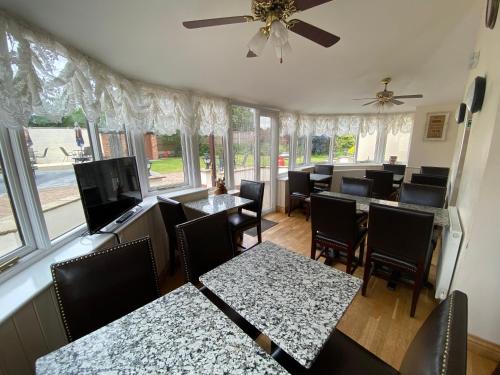 a dining room with tables and chairs and windows at Parkside Guest House in Pollington