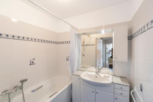 La salle de bains blanche est pourvue d'un lavabo, d'une baignoire et d'un lavabo. dans l'établissement Appartement Vue Mer Mandelieu, à Mandelieu-la-Napoule