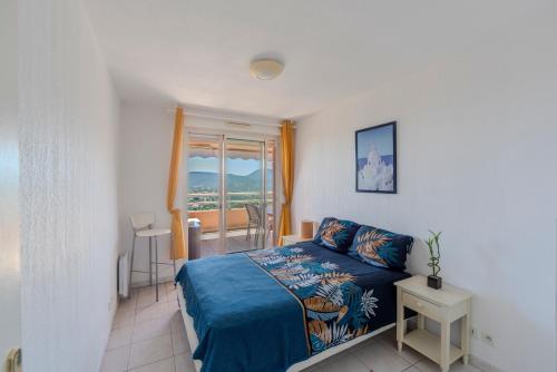 une chambre avec un lit bleu et une fenêtre dans l'établissement Appartement Vue Mer Mandelieu, à Mandelieu-la-Napoule