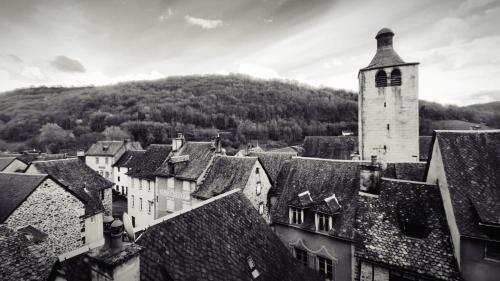 une photo en noir et blanc d'une ville avec une tour de l'horloge dans l'établissement L'échappée belle de l'Aubrac, à Saint-Chély-dʼAubrac
