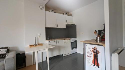 eine Küche mit weißen Schränken und einem Poster einer Frau in der Unterkunft Appartement d'une chambre avec wifi a Palaiseau in Palaiseau