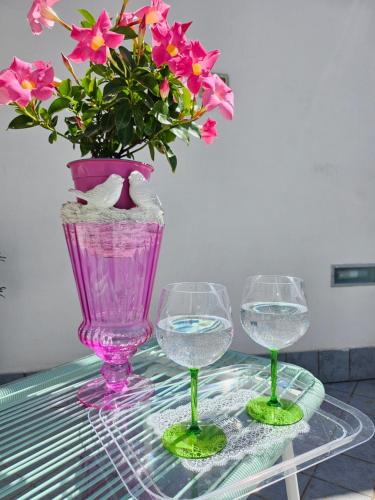 een tafel met twee wijnglazen en een vaas met bloemen bij Sky-Terrace in Central Station, 3 bedrooms in Napels