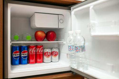 an open refrigerator with soda cans and apples in it at Dung Boutique Inn in Cat Ba