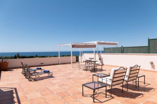 a patio with chairs and tables on a roof at Guadalpin Suites in Marbella
