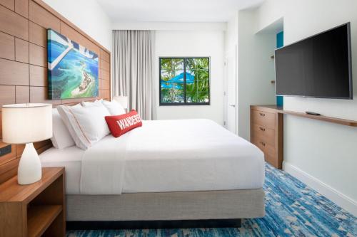 a hotel room with a bed and a flat screen tv at Compass by Margaritaville Hotel Naples in Naples