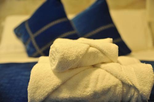 a pile of white towels on a bed with blue pillows at Ahuzat Shaul Seaside in H̱adera