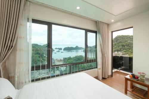 a bedroom with a large bed and large windows at Dung Boutique Inn in Cat Ba