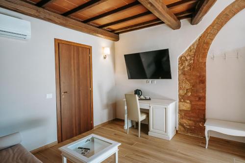 a living room with a table and a tv on the wall at Borgo Il Poggiaccio Residenza d'Epoca in Sovicille