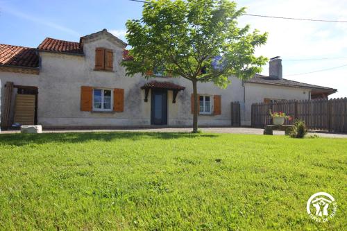 a house with a tree in front of a yard at Aux Belles Vignes in Réjaumont