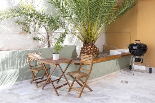 a table and two chairs and a table with plants at Oelia Rooms & Apartments in Agia Marina Aegina