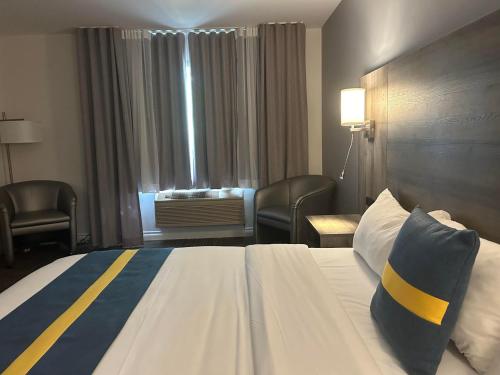a hotel room with a bed and chairs and a window at Hôtel Énergie Shawinigan in Shawinigan