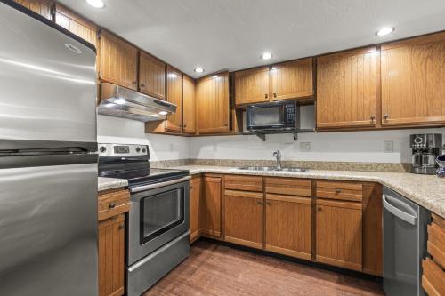 una cucina con armadietti in legno ed elettrodomestici in acciaio inossidabile di PARK STATION 121 condo a Park City
