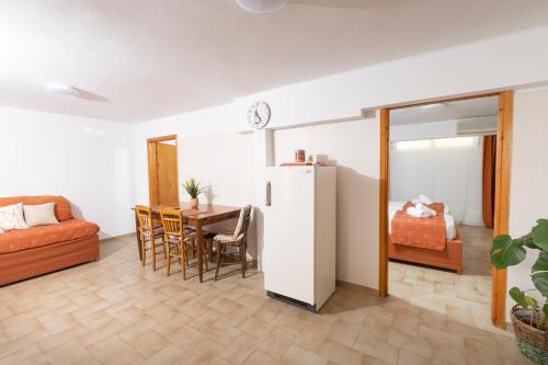 a living room with a table and a refrigerator at Oelia Rooms & Apartments in Agia Marina Aegina