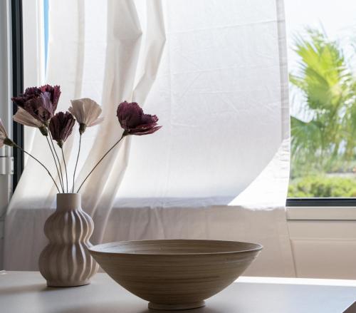 two vases with flowers sitting on a table next to a window at Marianthi Apts Anissaras in Hersonissos