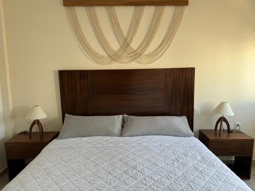 a bedroom with a bed with a wooden headboard and two lamps at Nabani Condominios T2 in Santa Cruz Huatulco