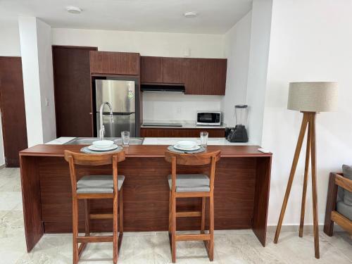 a kitchen with a wooden island with two chairs at Nabani Condominios T2 in Santa Cruz Huatulco