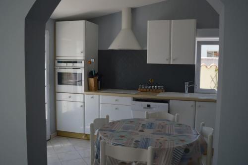 une cuisine avec des armoires blanches et une table avec des chaises dans l'établissement maison 8 pers 300m de la plage, à Dolus-d'Oléron