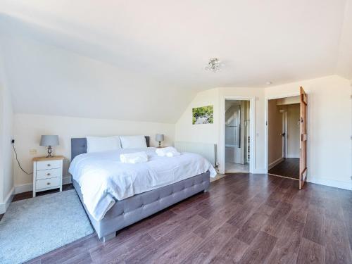 a bedroom with a large white bed and wooden floors at The Linhay in Watchet