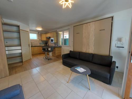 ein Wohnzimmer mit einem Sofa und einem Tisch in der Unterkunft Rare, cosy studio terrasse au coeur de St-Jorioz in Saint-Jorioz