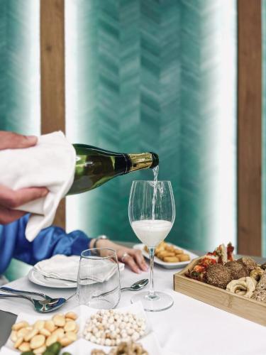 a person pouring white wine into a glass on a table at Maiorano Boutique Hotel in Manfredonia