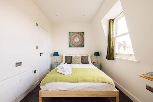 a bedroom with a bed with a green blanket at Wild Roses Serviced Apartments - Chelsea in London