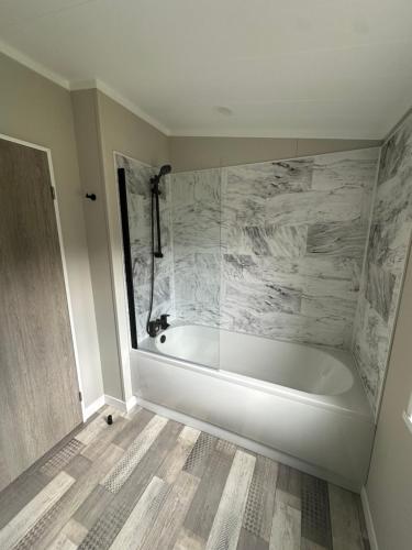 a white bath tub in a bathroom with marble at Cackle hill lakes, heron lodge in Biddenden