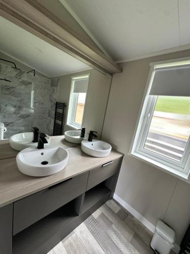 a bathroom with two sinks and a large mirror at Cackle hill lakes, heron lodge in Biddenden