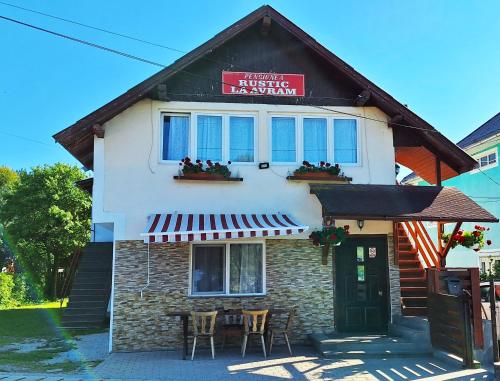 a building with a table and chairs in front of it at Pensiunea Rustica La Avram Lunca Ilvei in Lunca Ilvei