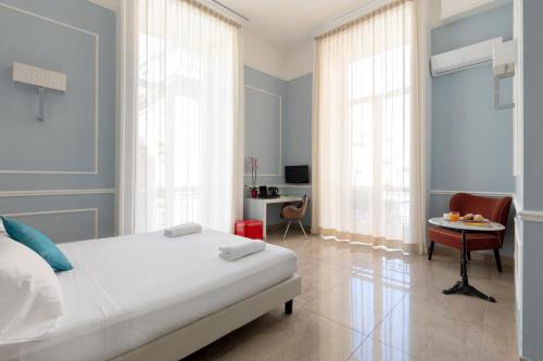 a bedroom with a bed and a desk with a chair at Napolit'amo Hotel Principe in Naples