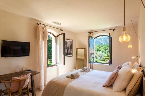 a bedroom with a bed and a desk and two windows at Bastide de l'Orme à Ménerbes avec vue Luberon in Ménerbes