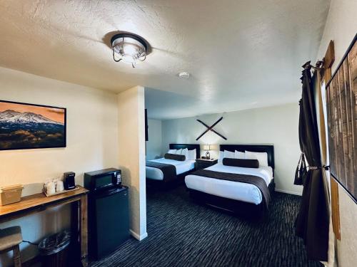 Cette chambre comprend deux lits et une télévision. dans l'établissement Shasta Inn, à Mont Shasta