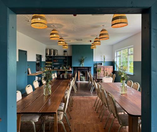 a dining room with wooden tables and chairs and a fireplace at The Common Knowledge Centre in Kilfenora