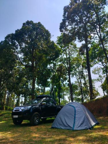 a tent and a jeep parked in a field at Forestscape Resort Munnar in Munnar