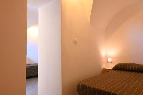 Una pequeña habitación con una cama y una habitación con una lámpara. en Casa dell'Alcova, en Ceriana