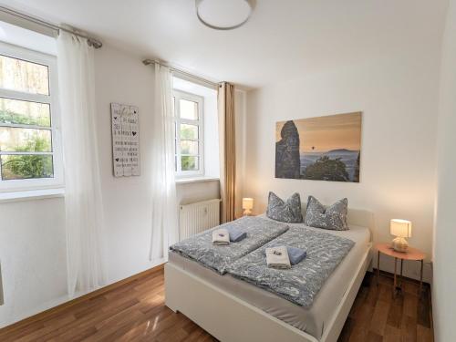 a white bedroom with a bed and two windows at HW1B - Urlaubsmagie Gemeinschaftsgarten mit Pool, Sauna & Terrasse in Sebnitz