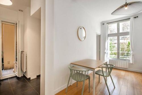 une salle à manger avec une table et des chaises et une fenêtre dans l'établissement Appartement centre Levallois Proche Paris, à Levallois-Perret