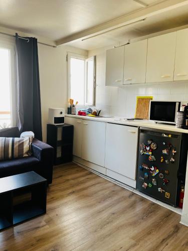 une cuisine avec des armoires blanches et un réfrigérateur noir dans l'établissement Charmant studio au centre de PARIS, à Paris