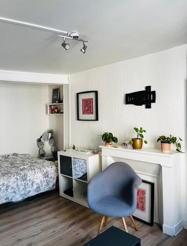 une chambre avec un lit et une chaise bleue dans l'établissement Charmant studio au centre de PARIS, à Paris