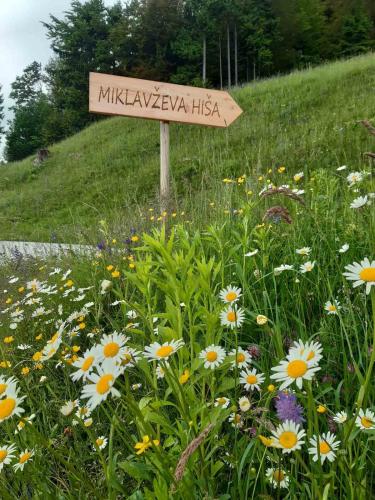 a sign in the middle of a field of flowers at Miklavževa hiša with a bread oven in Železniki